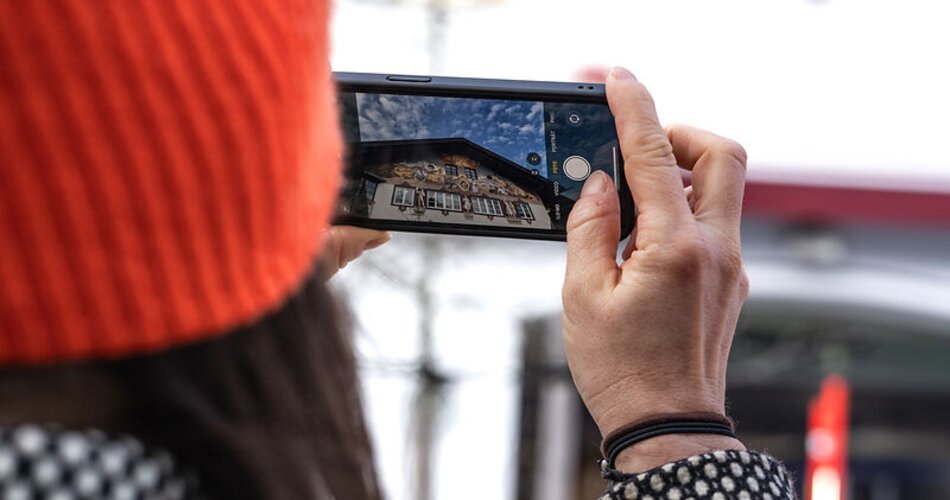 Blick durch ein Smartphone auf Lüftlmalereien bei einer Ortsführung durch Garmisch | © GaPa Tourismus GmbH/ Roadtrip the World